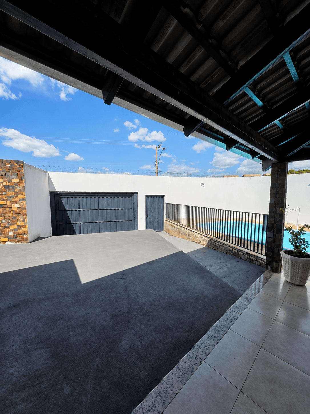 Pátio da área coberta da Vila Agostinis com grade de ferro e vista para a piscina.