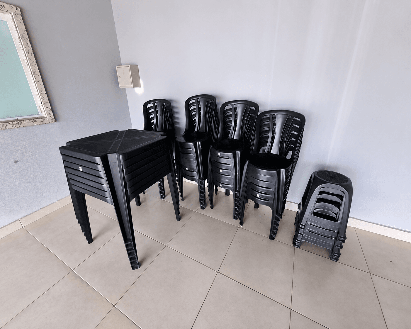 Mesas e cadeiras plásticas pretas empilhadas, guardadas na Vila Agostinis.