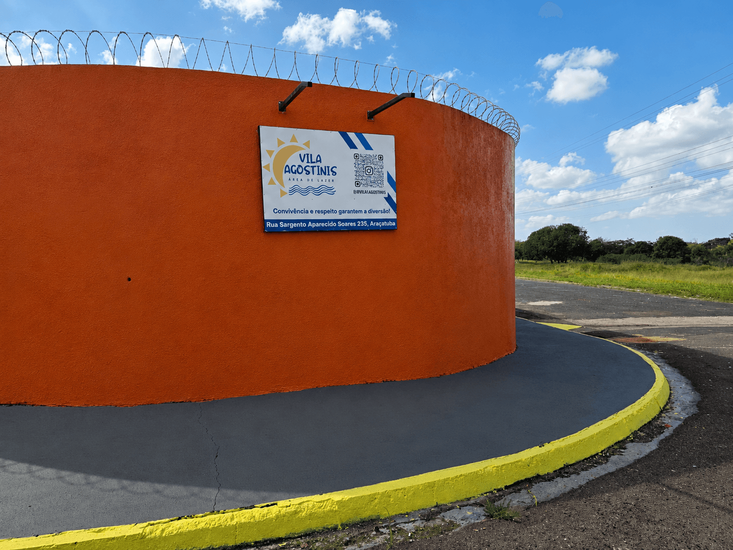 Placa de identificação da Vila Agostinis fixada no muro externo, com arame farpado no topo.